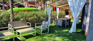 A patio area with outdoor furniture, a green kayak, and a covered seating area.