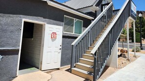 A building with a grey exterior, a white door with an 'EXIT' sign, and a staircase leading to the upper floor. - (PPV1) The Attic | Historic Hurricane (Hurricane)