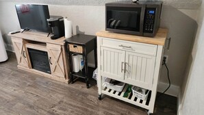 A kitchenette with a microwave, a coffee maker, and a TV on a wooden cabinet. - (PPV1) The Attic | Historic Hurricane (Hurricane)