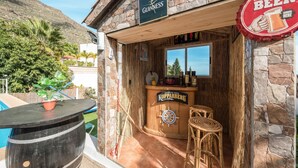 A wooden bar with a Guinness sign, a Koppaberg sign, and a beer bottle cap sign. - Vacation Home 'Casa Reina Del Atlántico' with Sea View, Private Pool and Wi-Fi (Candelaria)