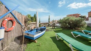A boat, a lifebuoy, a green lawn, and a building in the background. - Vacation Home 'Casa Reina Del Atlántico' with Sea View, Private Pool and Wi-Fi (Candelaria)
