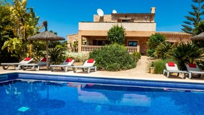 A pool area with lounge chairs and a building with satellite dishes. - Country house with pool and beautiful views (Cas Concos)