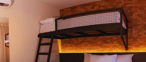 Una cama litera con escalera, una cama inferior y una pared de ladrillo.