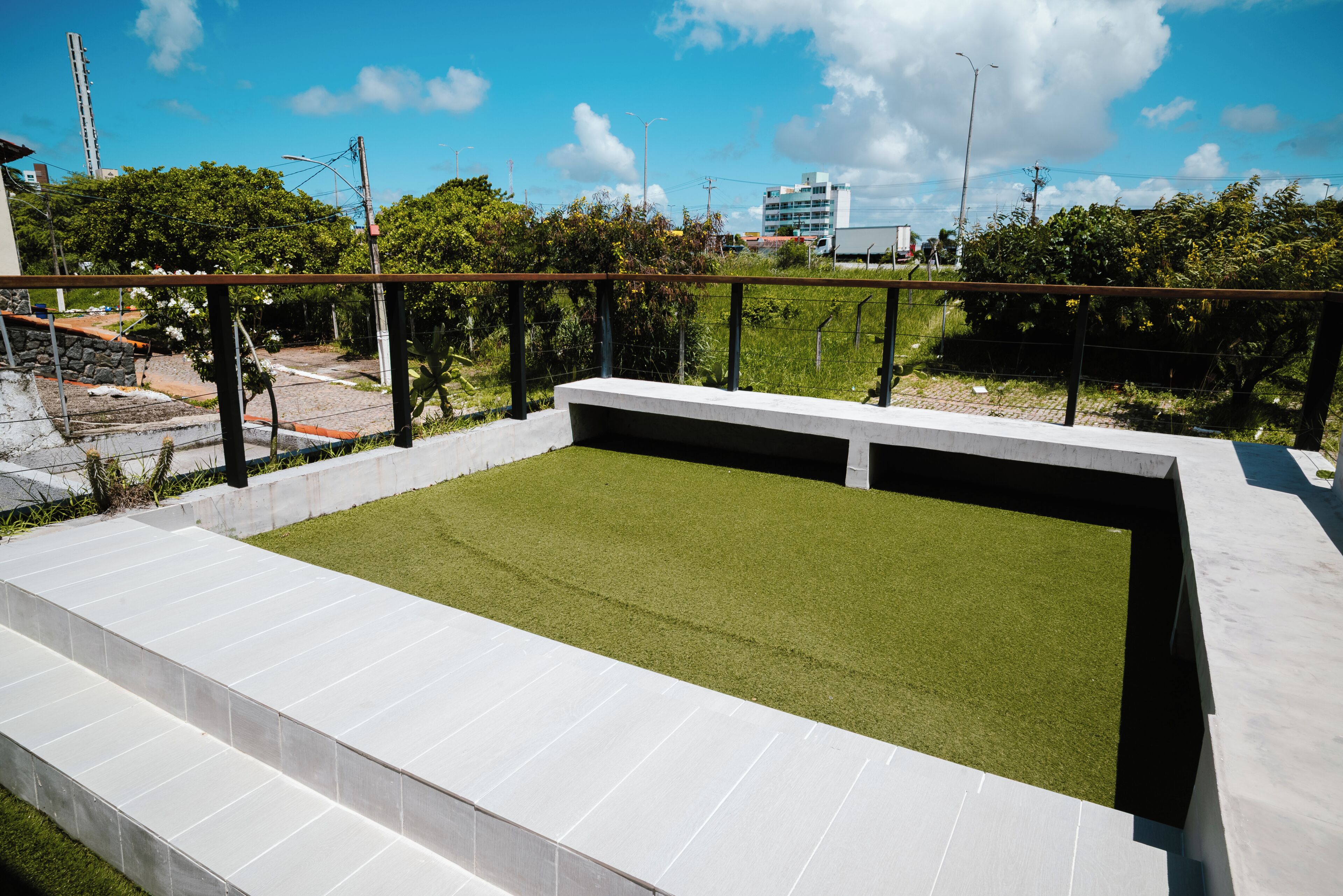 Une terrasse sur le toit, dotée d’un revêtement d’herbe artificielle, d’une rambarde et offrant une vue sur les environs.