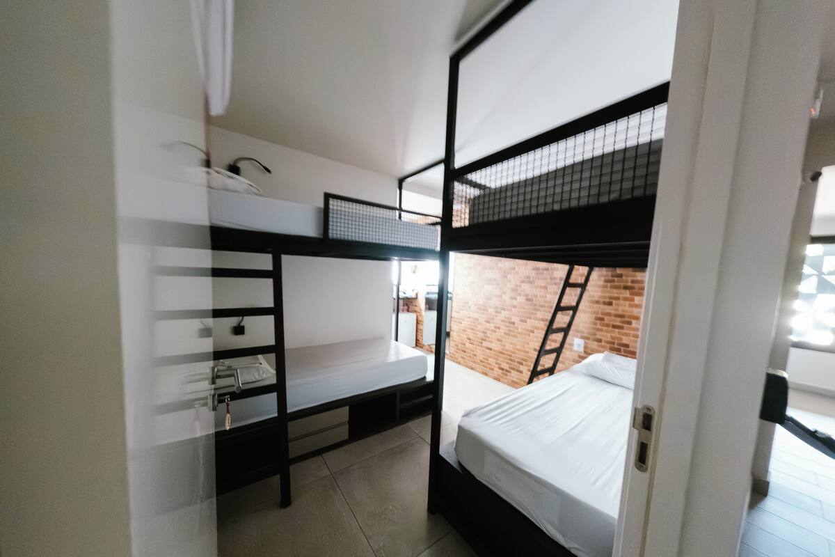 A compact room with bunk beds, a desk, and a ladder.