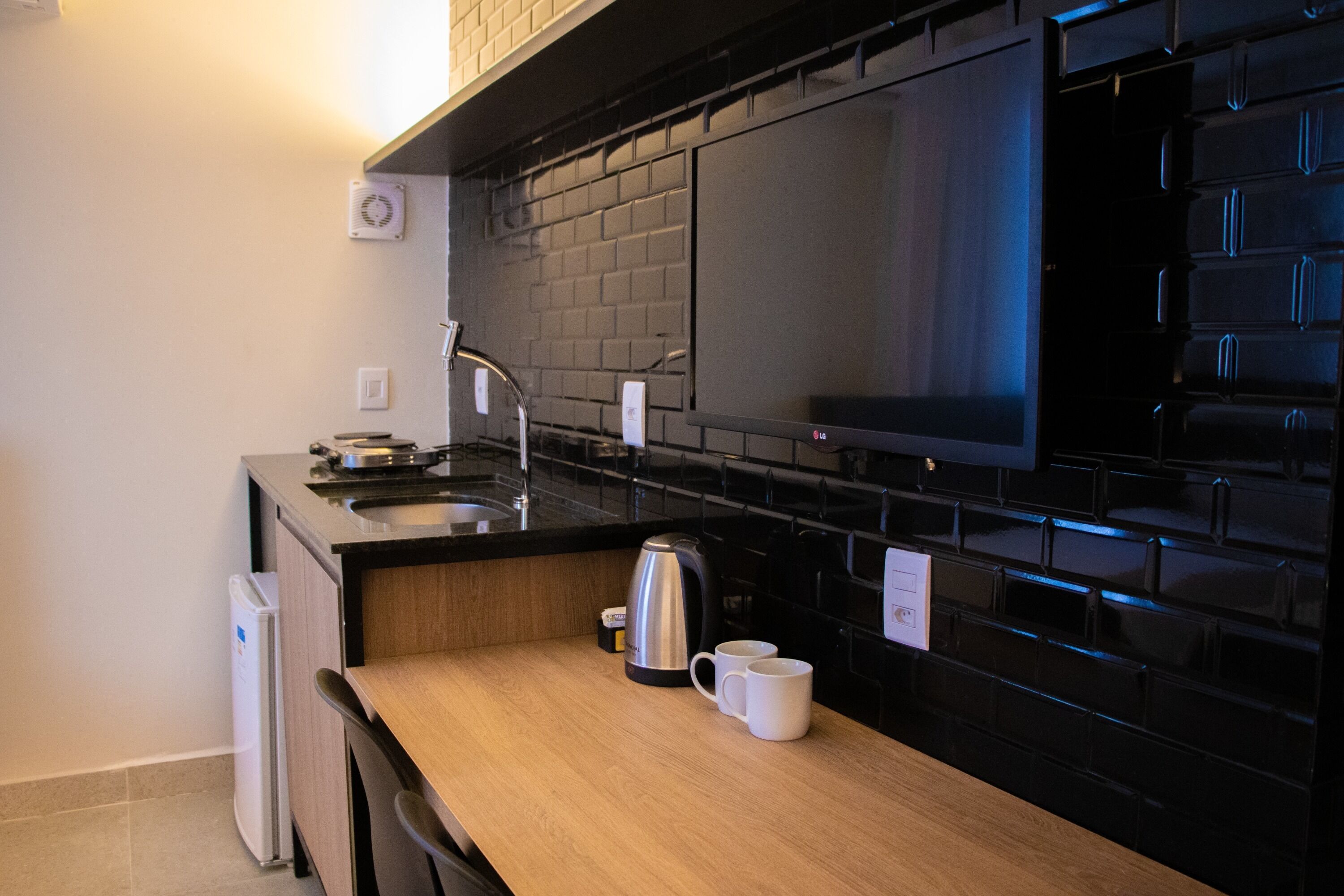 Cocina moderna con salpicadero negro, electrodomésticos de acero inoxidable y encimera de madera.