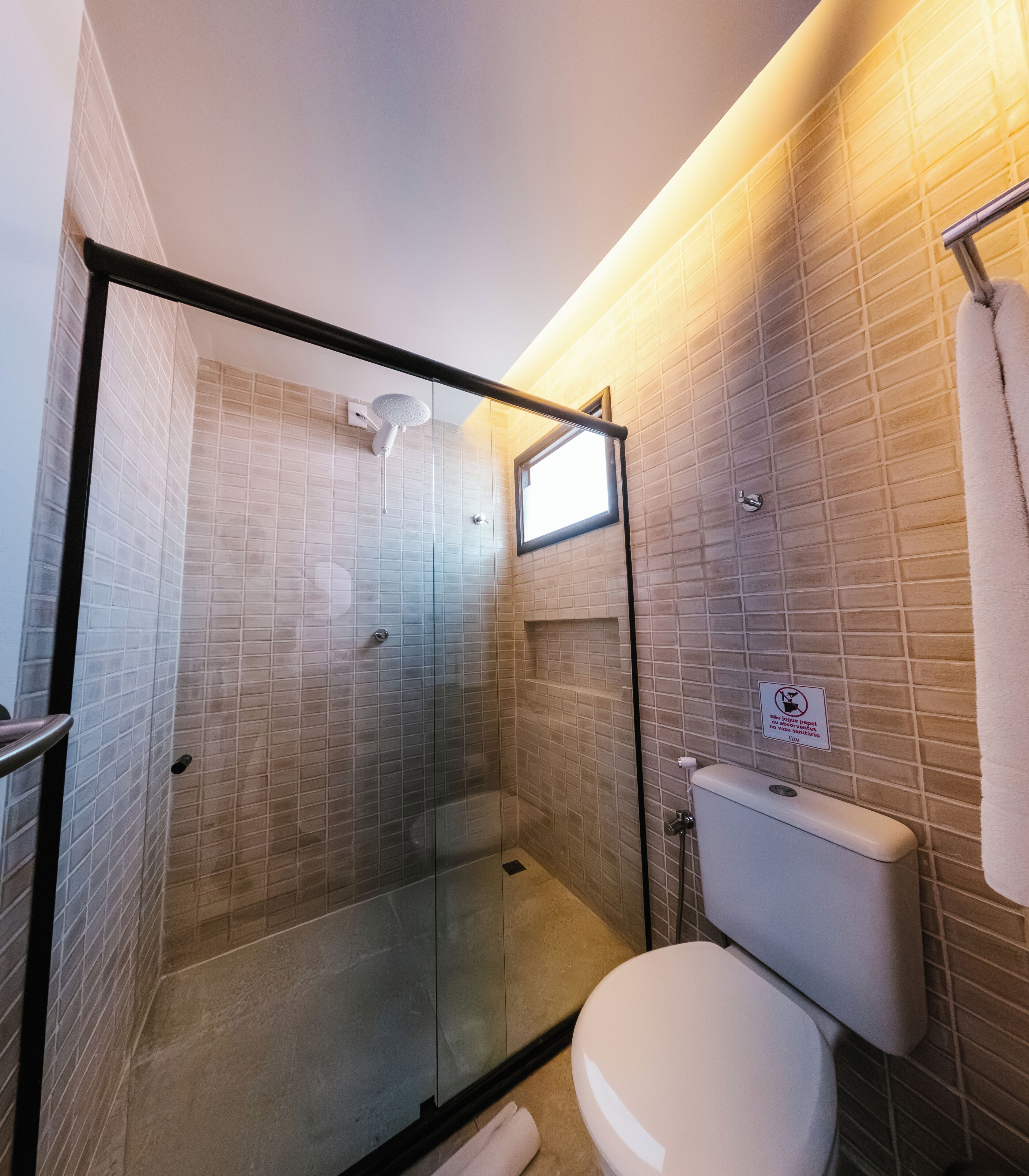 Un bagno moderno con cabina doccia in vetro, un water e un portasciugamani.