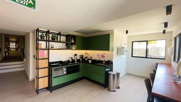 A compact kitchen with green cabinets, a built-in oven, and a sink. There is a sign above the sink indicating an exit.