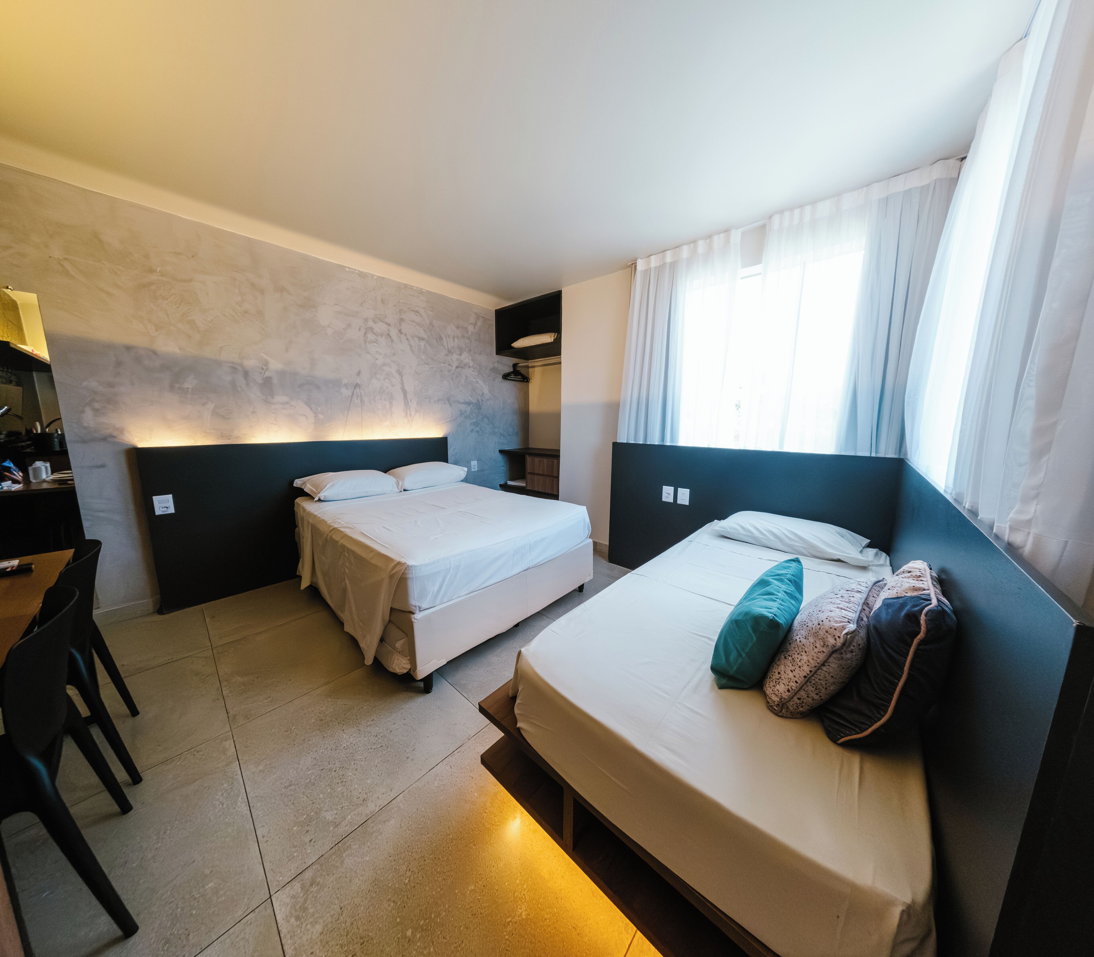A hotel room with two beds, a desk, and a chair.