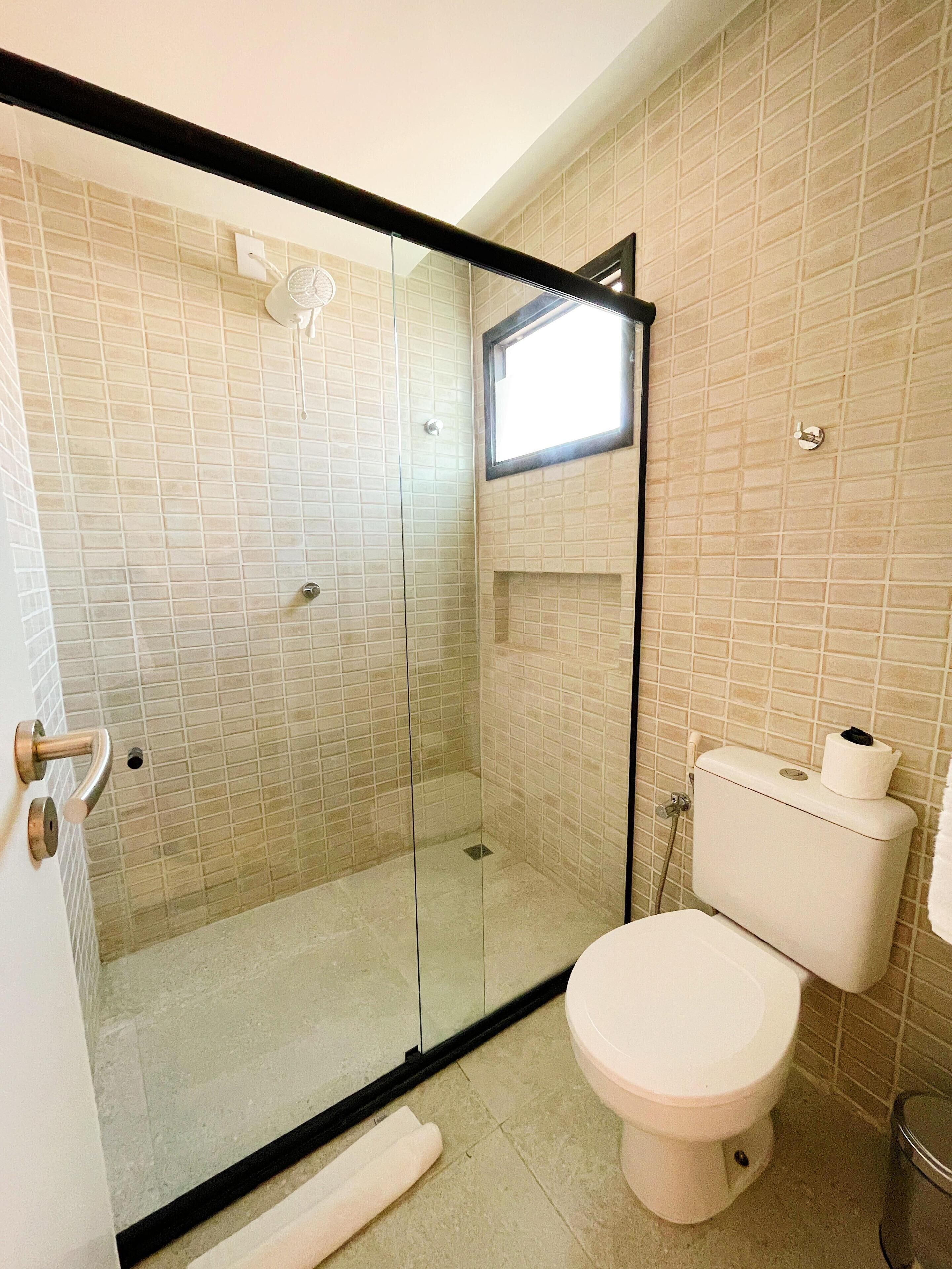 Une salle de bain avec une douche à parois de verre, des toilettes et un lavabo.