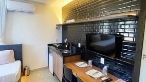 A compact hotel room with a kitchenette, a bed, and a small dining area. - Liiv Costeira - Natal Ponta Negra (Natal)