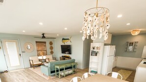 Een ruime keuken met een houten eettafel en stoelen, een witte koelkast en een plafondventilator.