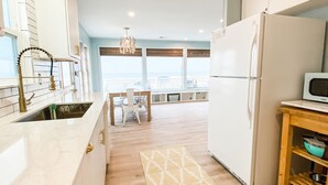 Een moderne keuken met een groot kookeiland, een eetgedeelte met uitzicht en een koelkast.