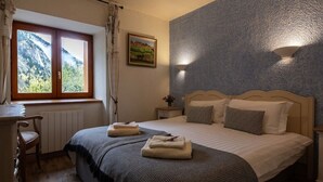 A bedroom with a bed, a desk, a window with a view of mountains, and a painting on the wall. - Private terrace, warm & cosy lounge with fireplace (Vaujany)