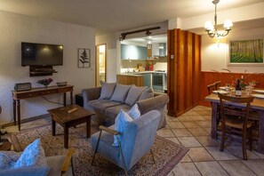 Een woonkamer met een bank, salontafel, televisie en een eethoek met stoelen en een tafel.