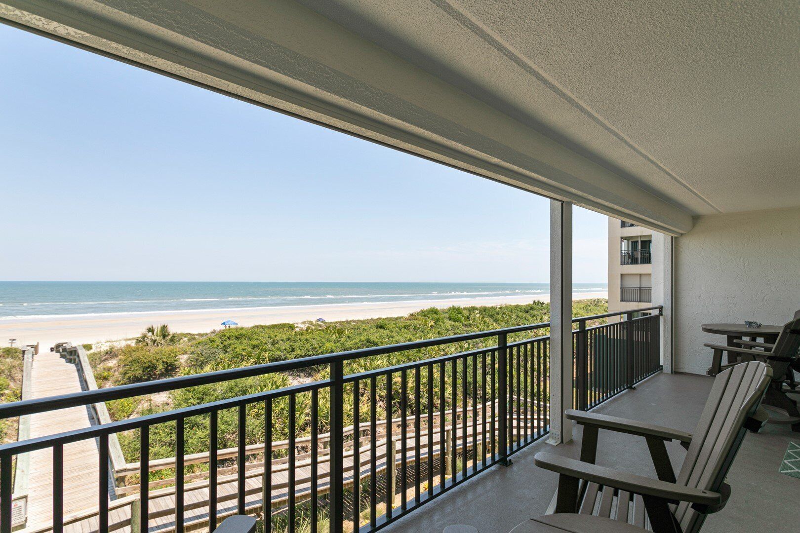 A balcony with a view of the beach and ocean.