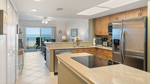 A modern kitchen with a large island, stainless steel appliances, and a view to the outside. - Windjammer 209 - 2 Bedroom Oceanfront Getaway (St. Augustine)