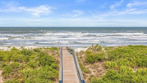 A wooden boardwalk leading to a beach with waves crashing onto the shore. - Windjammer 209 - 2 Bedroom Oceanfront Getaway (St. Augustine)