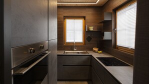 A modern kitchen with built-in appliances, a window with blinds, and wooden cabinetry. - Chalet Cirmolo (Livigno)