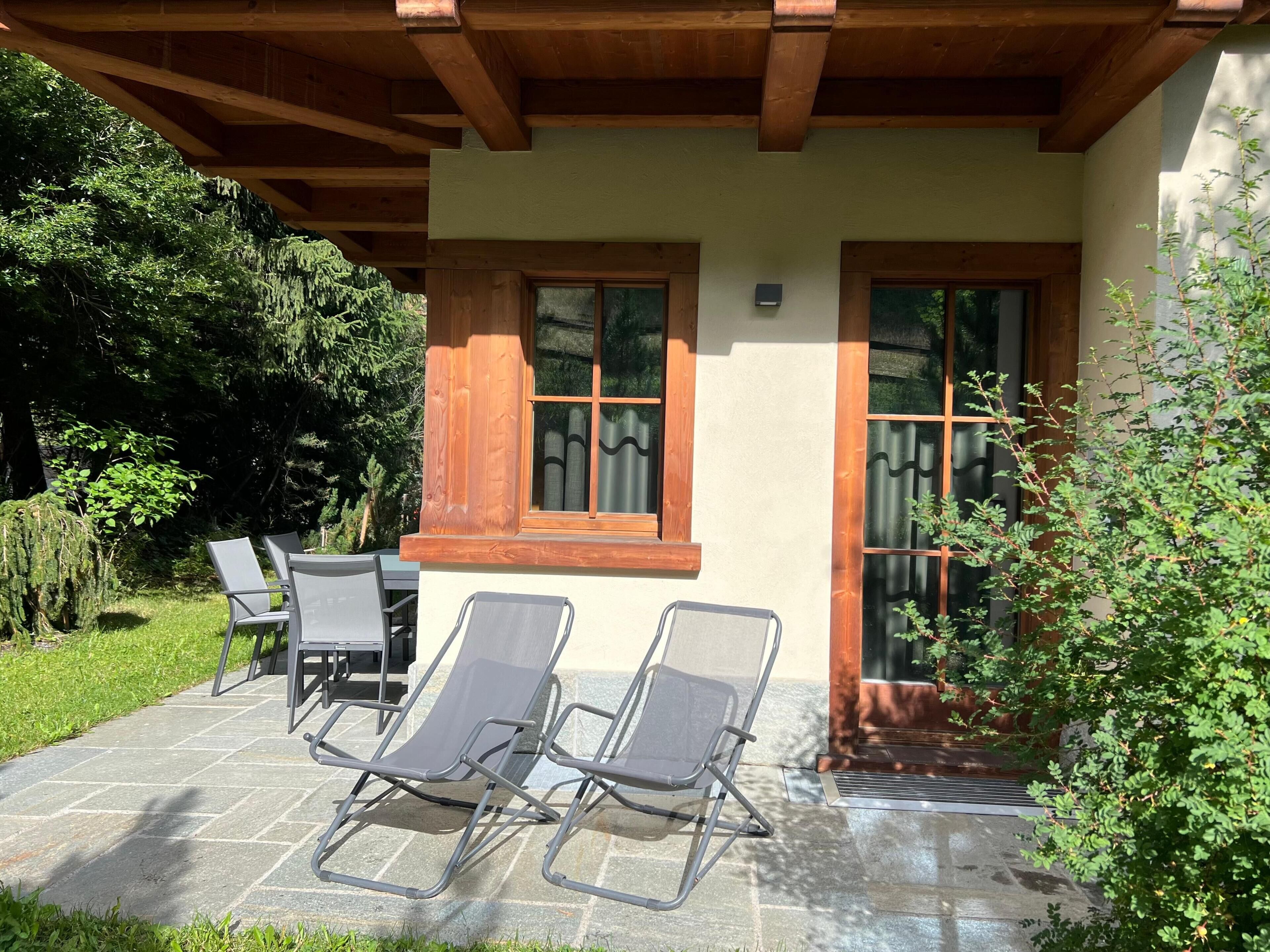A patio with two lounge chairs, a table, and a wooden pergola.