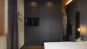 A modern bedroom with a large bed, a built-in wardrobe, a flat-screen TV, and a mirror with lights. - Chalet Cirmolo (Livigno)