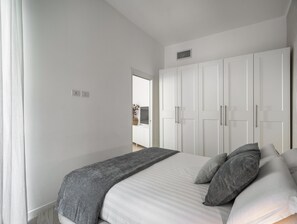 A bedroom with a bed, white wardrobe, and a door leading to a bathroom. - Brera Design Apartment R&R (Milano)