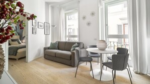 A modern living room with a sofa, chairs, a table, and a large window with curtains. - Brera Design Apartment R&R (Milano)