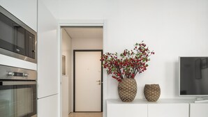 A modern kitchen with white cabinetry, a built-in oven, and a large flat-screen TV. - Brera Design Apartment R&R (Milano)