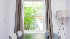 A conference room with a large table, six chairs, a floor lamp, and a window with curtains.