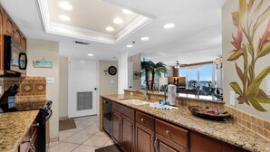 A kitchen with granite countertops, wooden cabinets, and a view of the ocean. - ✨Gulf & Harbor Views~Beachfront Pool~Wlk2Beach~Fitness Center~3BR East Pass 308 (Destin)
