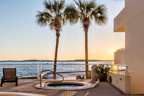 A spa area with a hot tub, palm trees, and a view of the sea.