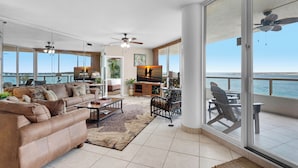 A spacious living area with a large sofa, coffee table, and a view of the ocean through large sliding doors. - ✨Gulf & Harbor Views~Beachfront Pool~Wlk2Beach~Fitness Center~3BR East Pass 308 (Destin)
