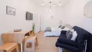 A modern, well-lit living room with a sofa, a dining table, and a TV. - Studio Blancarde 1 (Marseille)
