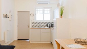 A compact kitchen with a window, a kettle, a microwave, and a refrigerator. - Studio Blancarde 1 (Marseille)