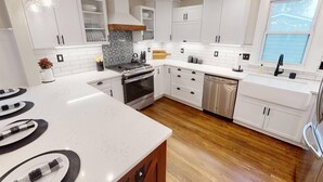 Una cocina moderna con armarios blancos, una estufa de acero inoxidable y un lavavajillas.