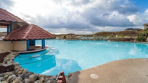 Une piscine dotée d’une terrasse carrelée, d’un espace salon couvert et d’une bordure en pierre.
