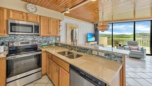 Une cuisine moderne avec des meubles en bois, des appareils électroménagers en acier inoxydable et un grand îlot central doté d’un évier.