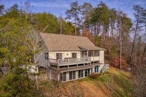 Uma casa de dois andares com varanda, rodeada por árvores.