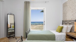 A bedroom with two beds, a large mirror, and a view of the beach. - Beachfront Villa Alexandra (Σκάλα)