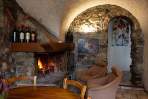 A stone-walled room with a fireplace, wooden furniture, and a painting.