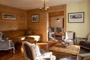 L’intérieur d’un chalet confortable, avec un canapé, des fauteuils, une table basse et une cheminée.