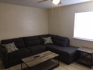 A living room with a sectional sofa, a coffee table, and a small side table.
