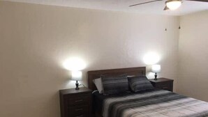Un dormitorio con una cama de madera, dos mesitas de noche con lámparas y suelo de madera.