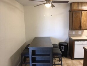 A compact kitchen with a dark countertop, wooden cabinets, and a ceiling fan.