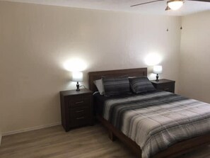 A bedroom with a bed, two bedside tables, and a ceiling fan.