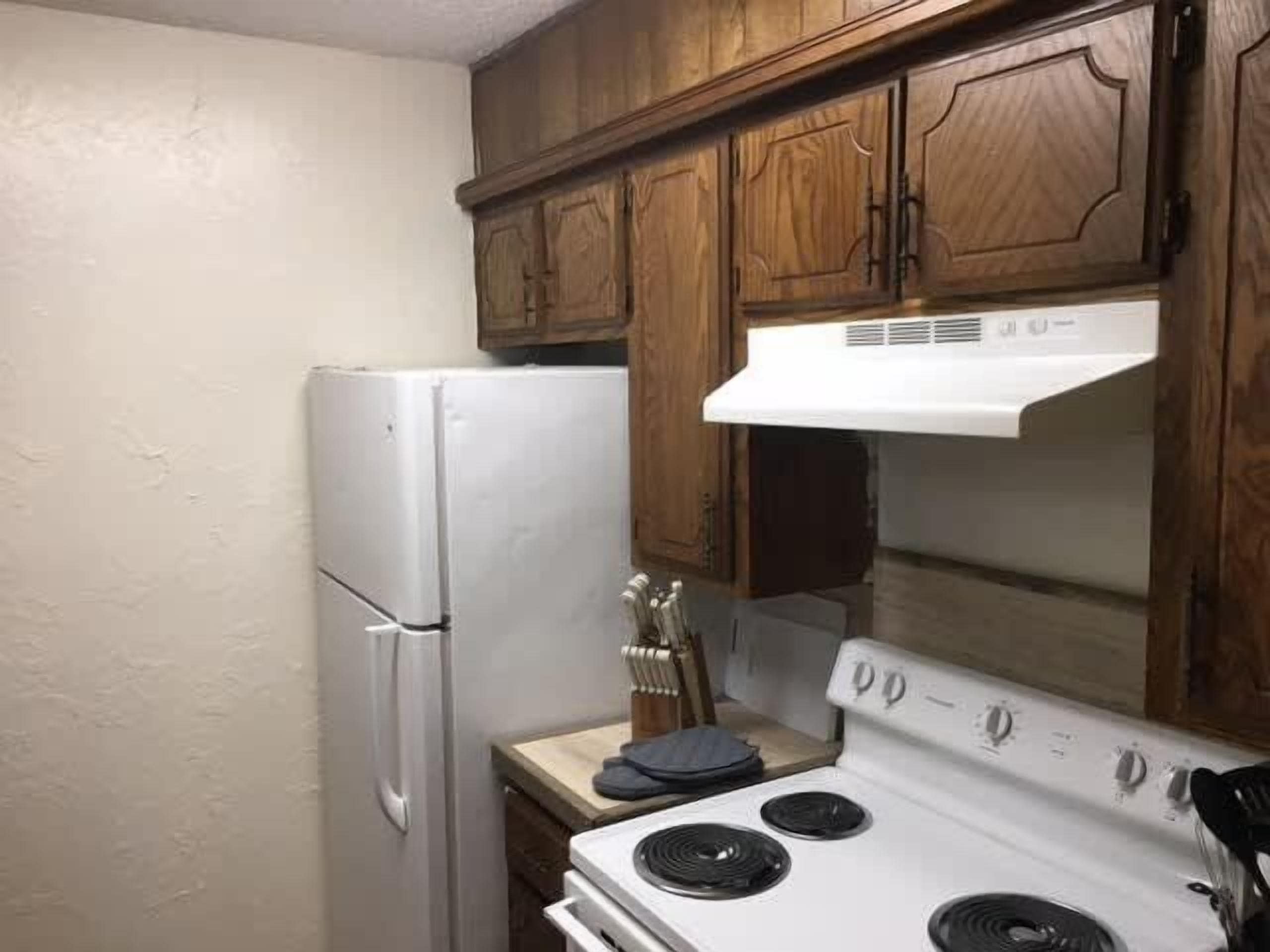A kitchen with wooden cabinets, a white refrigerator, and a stove.