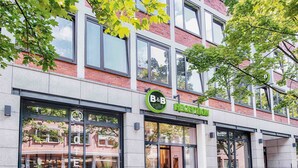 Un hôtel doté d’un espace de réception, de grandes fenêtres et d’une enseigne indiquant qu’il propose également un service de chambre et de petit-déjeuner.
