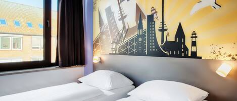 Een hotelkamer met twee bedden, een groot raam en een stadsgezicht muurschildering.