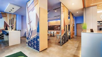 Eine moderne Hotelhalle mit Rezeption, Sitzgelegenheiten und einem großen Wandbild.