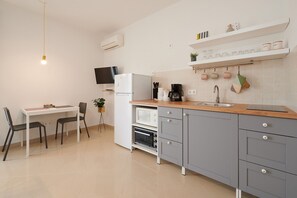 Une cuisine moderne avec un coin repas, comprenant une table, des chaises, un réfrigérateur, un four à micro-ondes et une machine à café.